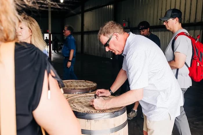 A man stencilling his name onto a barrel head